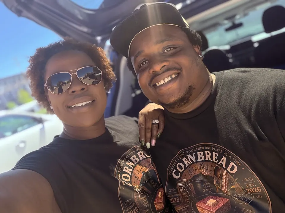 The owners of Cornbread & Company smiling together in branded shirts