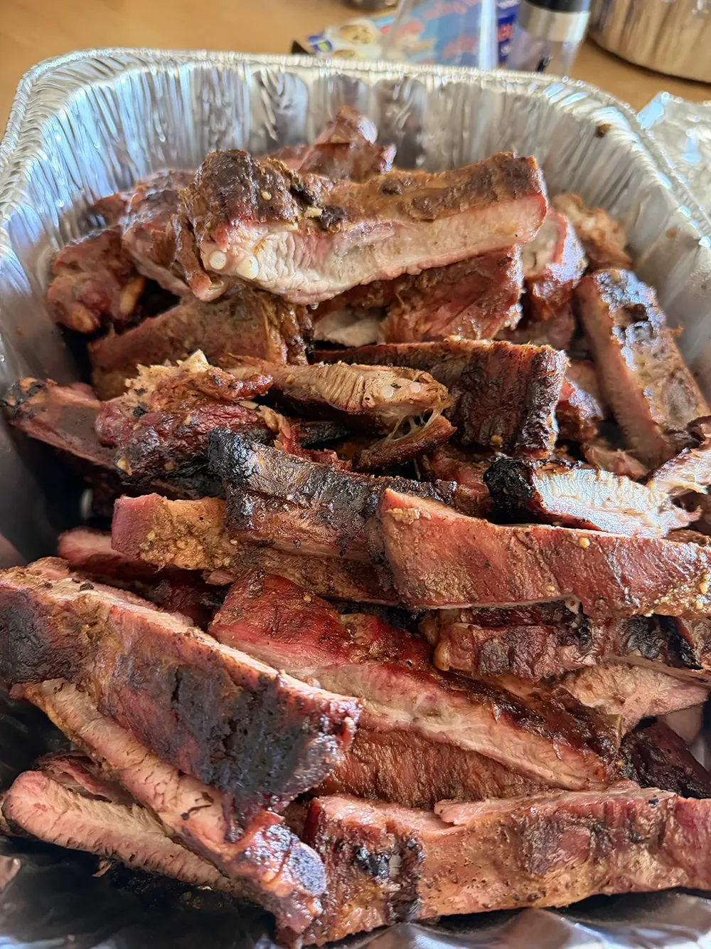 A catering pan piled with sliced barbecue ribs
