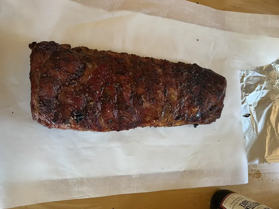 A rack of barbecue ribs resting on parchment paper